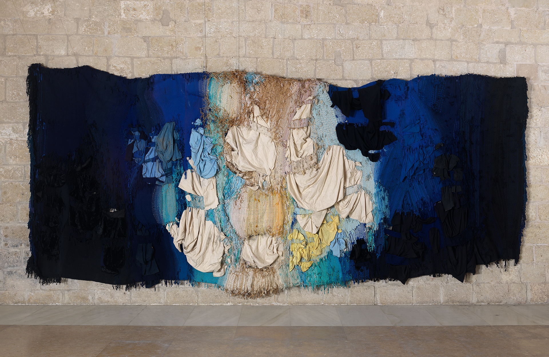 Josep GRAU-GARRIGA (1929 – 2011) | Hores de llum i de foscor | 1986 | Cotton, wool, silk, synthetic fibers, sheets and clothes (blue jeans, pajamas, tee-shirts) | 320 × 700 cm | FGA-BA-GRAUG-0001 | © Photo credit: Succession Josep Grau-Garriga | Photographer : Fotogasull SL, courtesy of Fondation Gandur pour l’Art